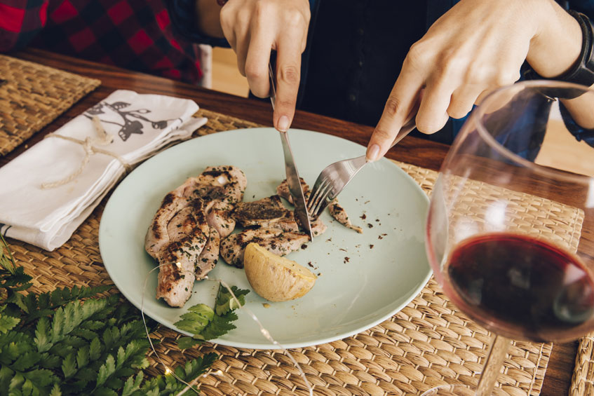 Two hands cut food onto plates